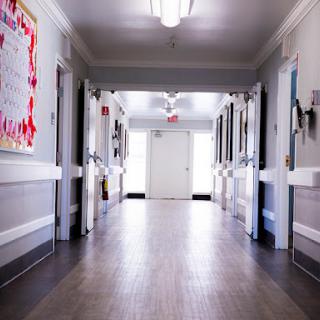A quiet hospital hallway with doors leading to patient rooms.