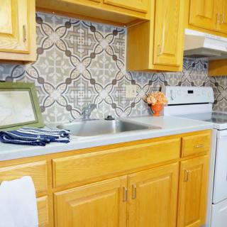 A bright kitchen with wooden cabinets, a patterned tile backsplash, and modern appliances.