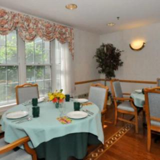 A cozy dining room with elegantly set tables and large windows allowing natural light to fill the space.