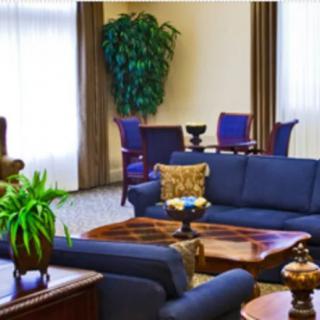 A cozy living room with blue sofas and a wooden table, adjacent to a dining area.