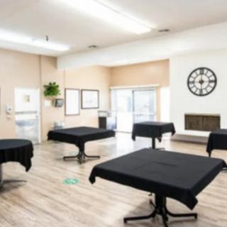 A modern interior room with tables covered in black tablecloths and a large clock on the wall.