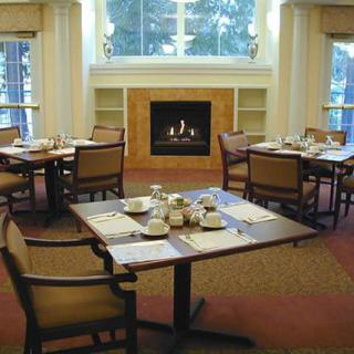 A cozy dining room with neatly set tables and a fireplace.