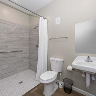 A modern bathroom with a walk-in shower, toilet, and sink.