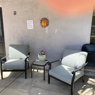 A cozy patio setup with two chairs, a small table, and decorative wall hanging.