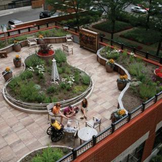 An urban rooftop garden with outdoor seating and lush greenery.