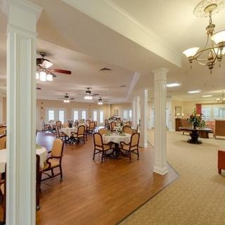 An elegantly designed dining room with multiple tables and chairs, featuring warm lighting and wooden flooring.
