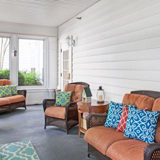 A cozy indoor porch with comfortable seating and colorful cushions.