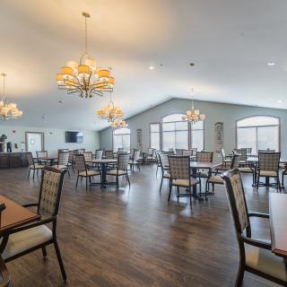 A spacious dining area with elegant chandeliers and neatly arranged tables and chairs.