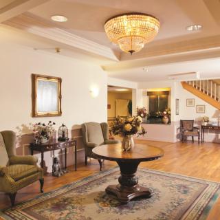A cozy lobby area with elegant furnishings and a central table beneath a chandelier.