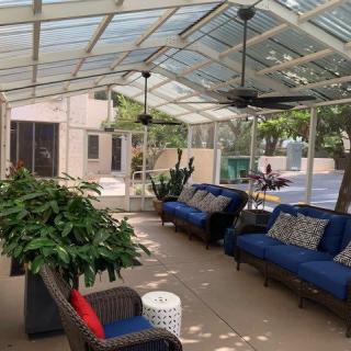 A spacious outdoor patio with comfortable seating and lush plants under a glass roof.