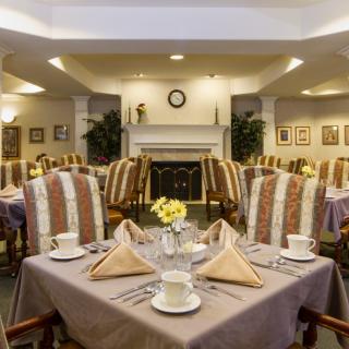An elegantly set dining room with neatly arranged tables and chairs, featuring decorative napkins and fine tableware.