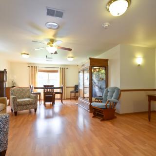 A spacious living and dining area with wooden flooring, cozy seating, and bright lighting.