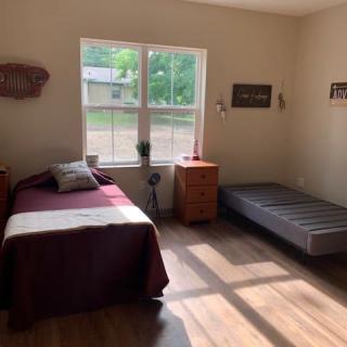 A simple and minimalist bedroom with two beds bathed in sunlight from a large window.