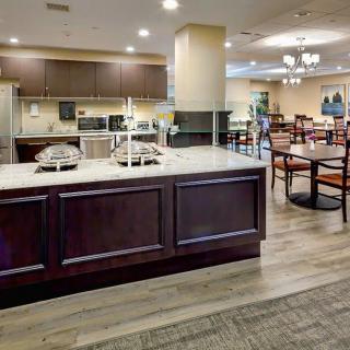 A modern dining area with a kitchen setup, featuring wooden furniture and soft lighting.