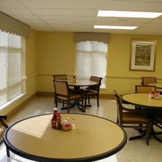 An empty dining area with round tables and chairs, featuring condiment bottles on the tables.