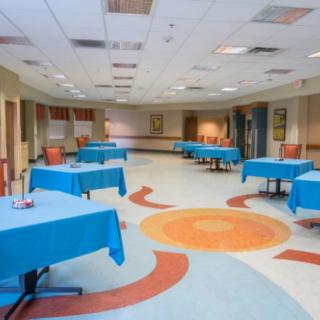 A spacious conference room with tables covered in blue tablecloths, arranged for an event or meeting.