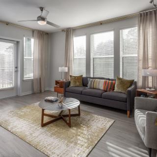 A modern living room featuring a comfortable sofa, stylish coffee table, and large windows with soft curtains.