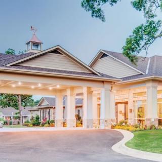 A well-lit building entrance with a covered driveway and columns.