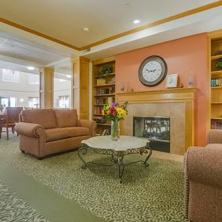 A cozy living room area with couches, a fireplace, and a decorative clock on the mantel.