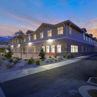 A modern commercial building exterior with lights on during the evening.