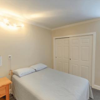 A minimalist bedroom with a bed, nightstand, and closet.