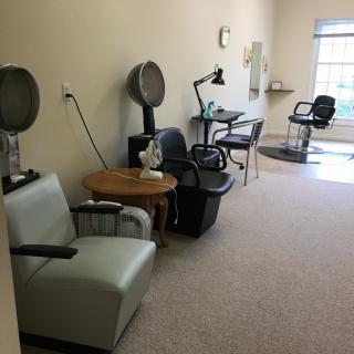 An interior view of an empty salon with hairdryers and styling chairs.
