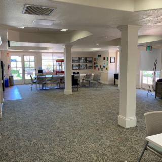 Spacious community area with tables and chairs, well-lit with natural light from large windows.