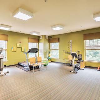 A bright and spacious gym with exercise equipment, including a treadmill and stationary bike.