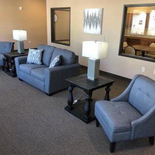 A cozy living room area featuring blue sofas and armchairs, paired with tables and lamps for a comfortable setting.