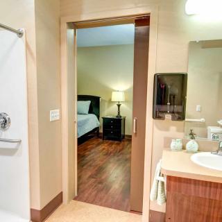A view from a bathroom into a bedroom, showcasing the shower, sink, and modern interior design.