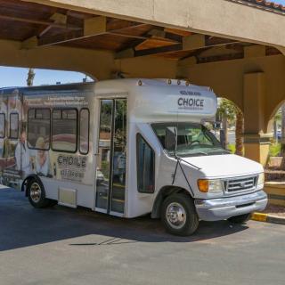 A hotel shuttle bus parked under a covered area.