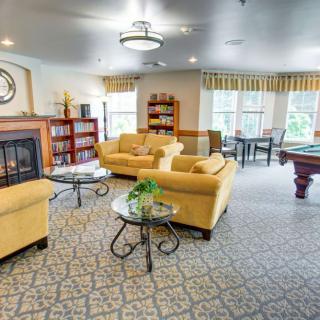 A cozy and spacious living area featuring comfortable sofas, a fireplace, and a pool table.