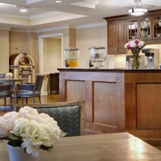 A cozy kitchen area featuring a wooden bar counter with flowers and coffee-making equipment.