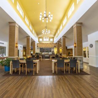 A spacious dining area with wooden furnishings and elegant chandeliers.