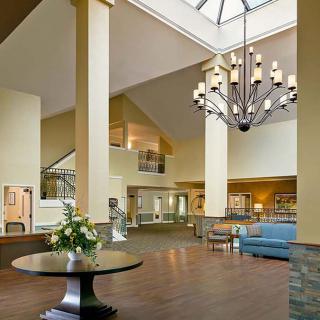 A spacious lobby featuring a large chandelier, skylight, and elegant furniture.