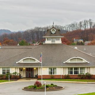 A suburban building with a clock tower, surrounded by landscaped grounds and set against an overcast sky.