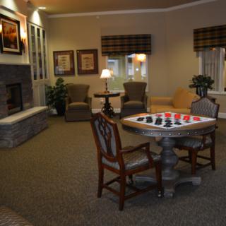 A cozy living room with a fireplace, seating area, and a table set up for chess.