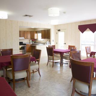 A spacious dining area with multiple tables and chairs adjacent to a kitchen.