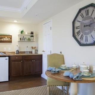 A cozy kitchen and dining area with a large wall clock and table set for two.