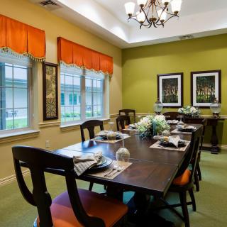 A well-decorated dining room with a long table and chairs, featuring vibrant curtains and elegant lighting.