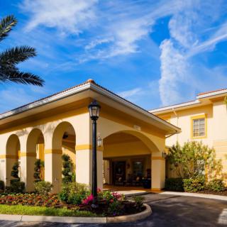 Entrance to a hotel with a clear blue sky and landscaped surroundings.