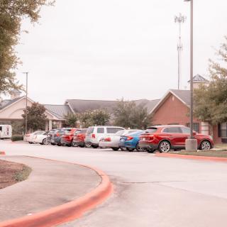 A row of cars parked outside a series of brick buildings on an overcast day.