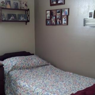 A cozy bedroom featuring a neatly made bed and personal photographs displayed on the wall.