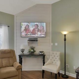 A cozy living room featuring a mounted television, comfortable seating, and elegant decor.