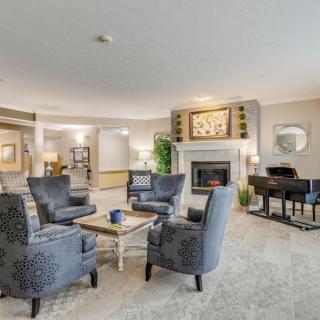 A cozy living room with a fireplace, comfortable seating, and a piano.