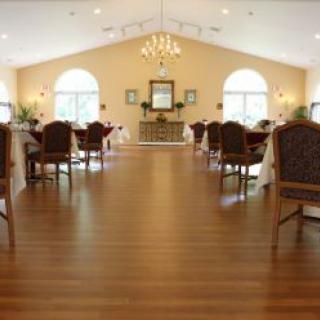 A spacious dining room with wooden flooring, a chandelier, and large windows.