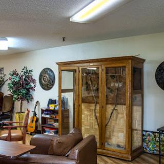A cozy living room featuring a wooden cabinet, comfortable seating, musical instruments, and decorative elements.