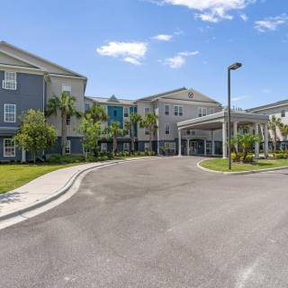 Exterior view of a residential building with palm trees and a driveway.
