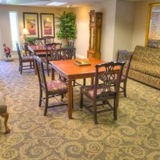 A well-furnished living room with a table, chairs, and sofa on a patterned carpet.
