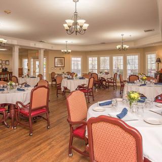 An elegant dining room with neatly arranged tables and chairs, set for a meal.